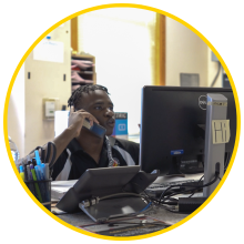 student worker behind service desk answering a phone call and looking at a computer monitor