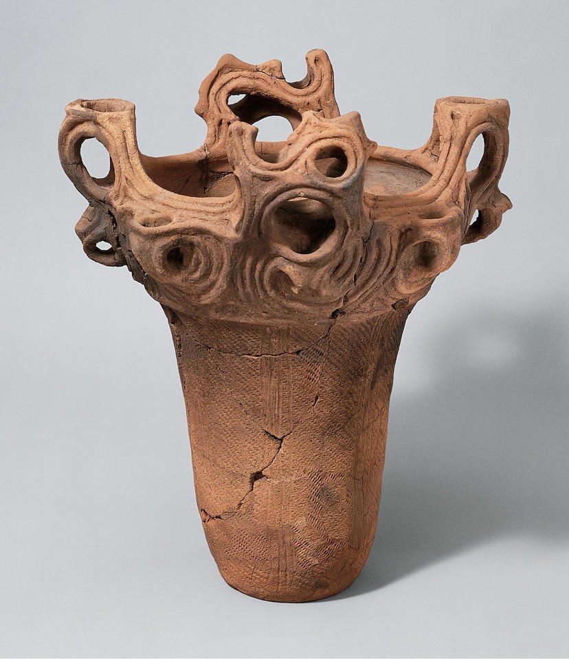 Light brown ceramic pot with a flat bottom and wavy, spiky decoration around the upper rim