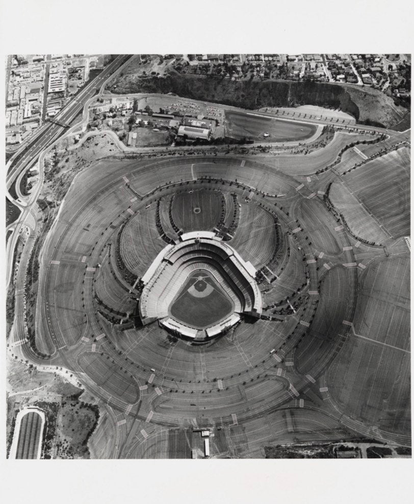 An aerial photograph in black-and-white depicting LA's Dodger's Stadium and its parking lot.