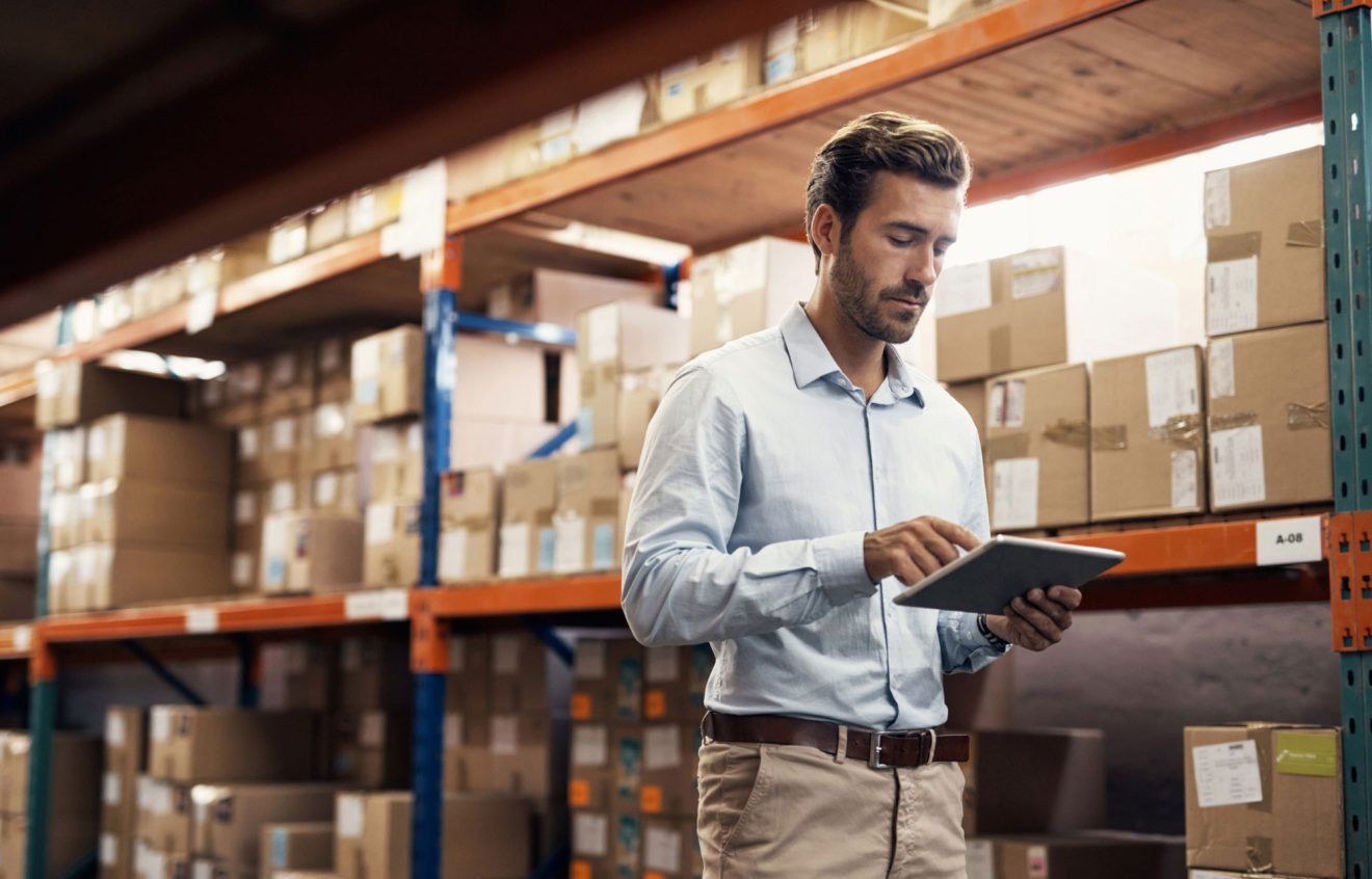 A man in a warehouse uses Quickbase on a tablet