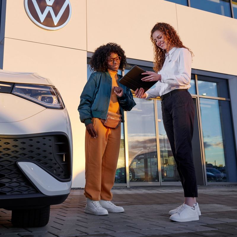 VW service employee and customer looking at a tablet next to a VW ID.5 –  Service for ID.