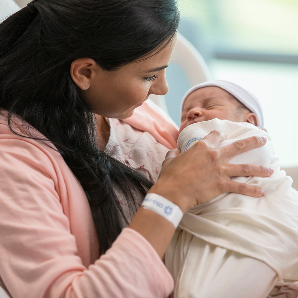 A woman wearing an OhioHealth hospital ID badge holds her Newborn