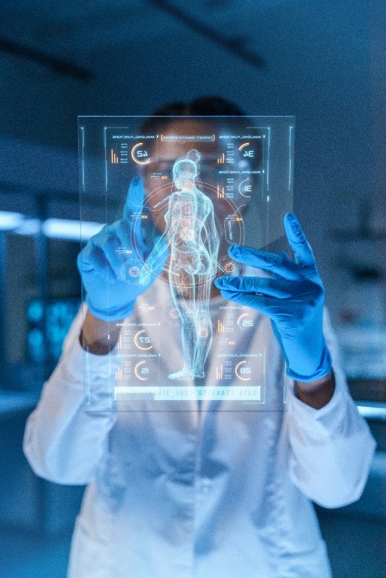 A person in a white lab coat and blue gloves touching a screen with a holographic human body and data readouts.