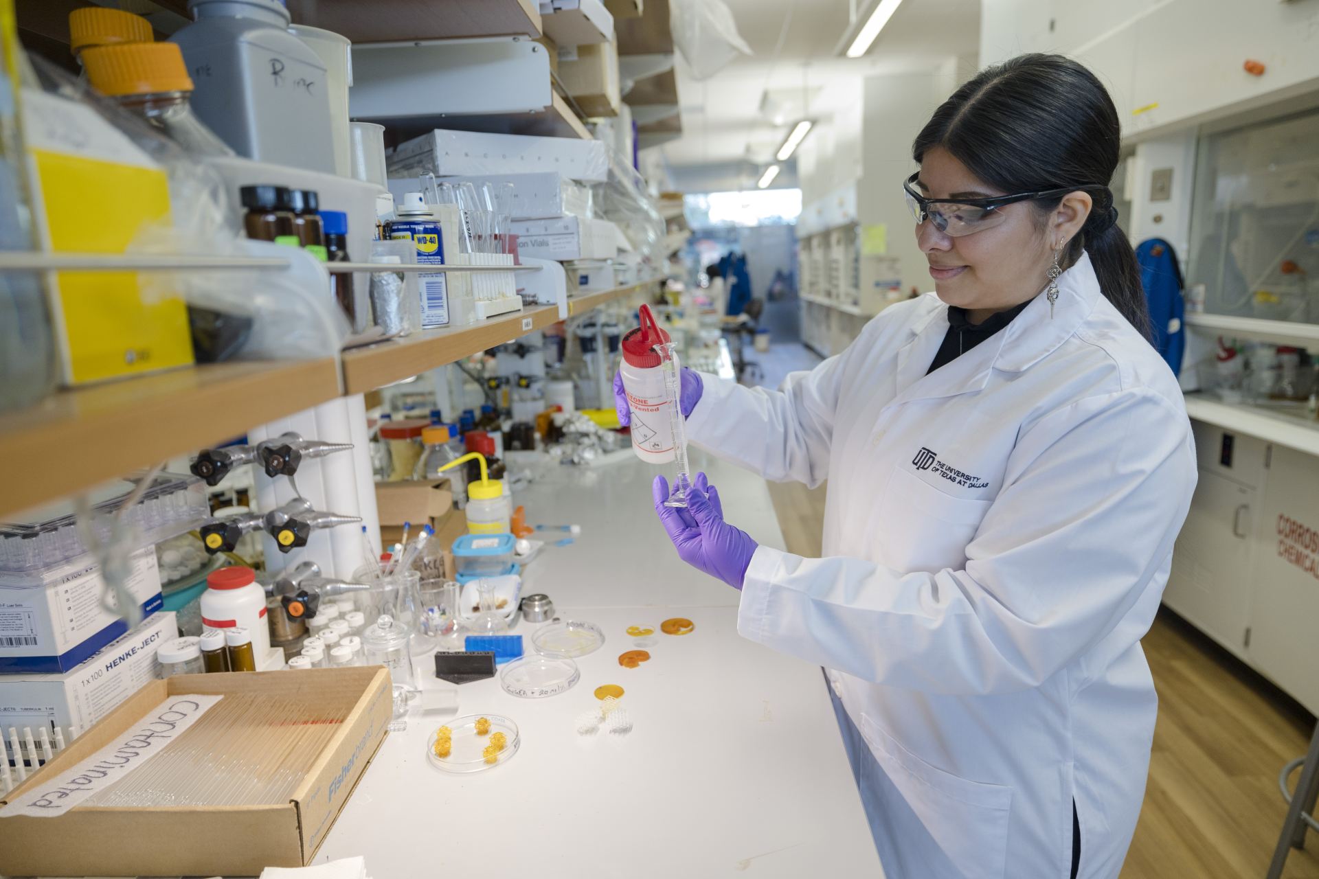 Photo of a student in lab adding acetone into a graduated cylinder for an experiment.