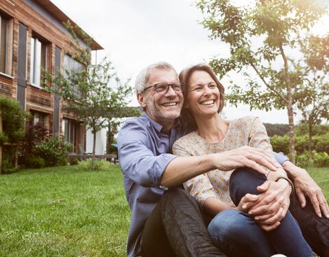 Couple assis l'un contre l'autre sur le chemin devant leur maison