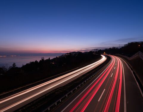 Photo à long terme d'une autoroute. A gauche, on voit des arbres et le lac.