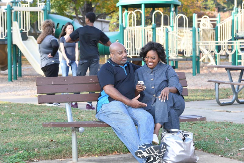 A couple sitting on a bench behind the play