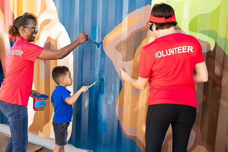 Two women and a kid painting a wall