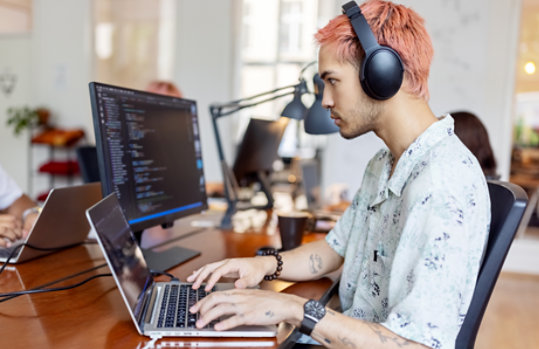 Un homme portant un casque travaillant sur son ordinateur portable au bureau.