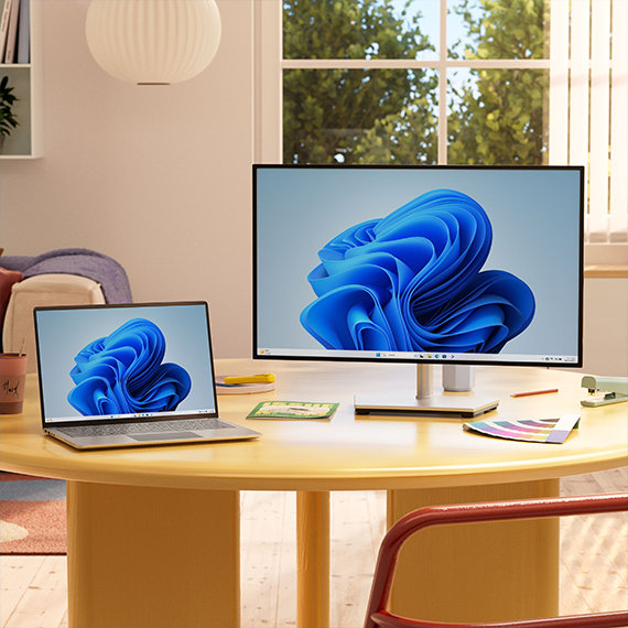 Laptop and desktop computers with Windows bloom on the screen sitting on a table