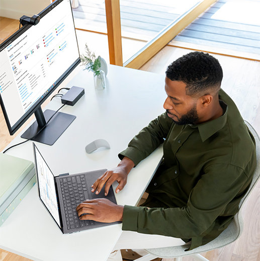 Un homme assis dans son bureau, utilisant un Surface Laptop