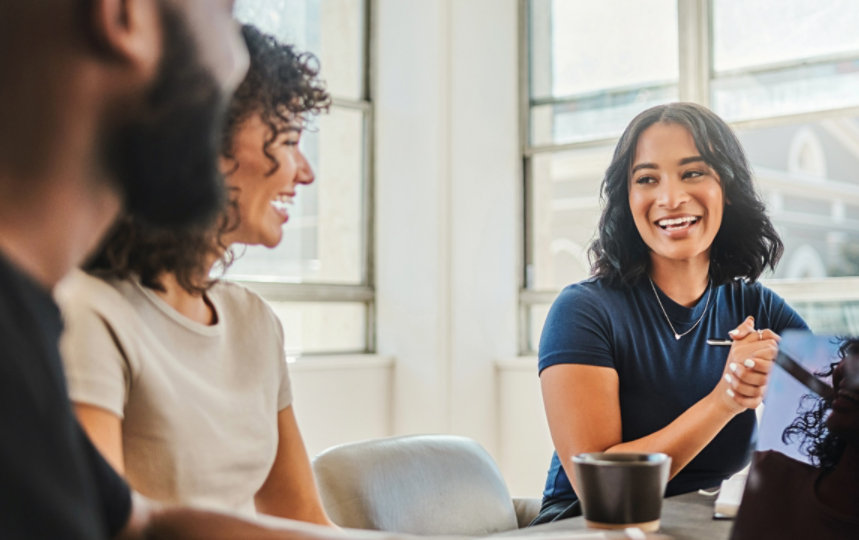 A diverse group of coworkers collaborate around a table with laptops.