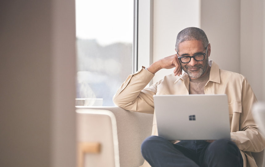 Man using his Surface laptop on a couch.