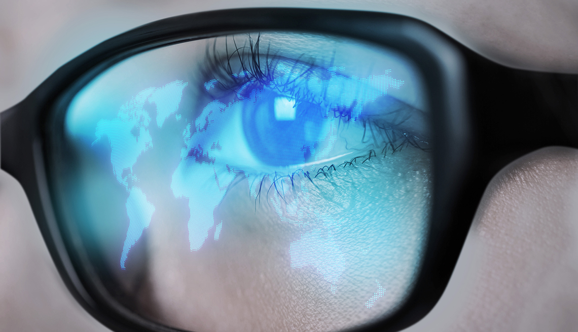 a glowing world map from a computer screen is reflected in a womans eyeglasses 