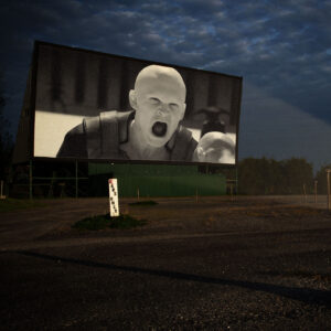 A drive in movie screen showing a scene from Dune 2, there's a sign that says CARS ONLY with the C crossed out