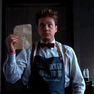 goofy looking man in 1950s mailroom apron holding up a piece of paper with a circle drawn on it