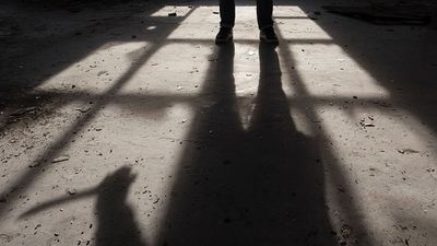 Shadow of a man holding large knife in his hand inside of some dark, spooky buiding