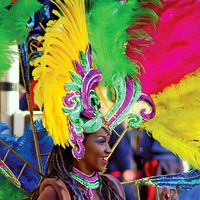 A woman with a brightly-colored feather headdress and costume, during a Carnival parade in Rio de Janeiro. Rio Carnival. Brazil Carnival.