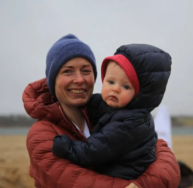 A woman holding a baby in her arms on a beach.