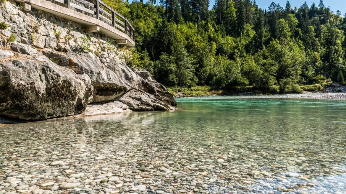 Ein Flussbett mit klarem Wasser und einer Brücke