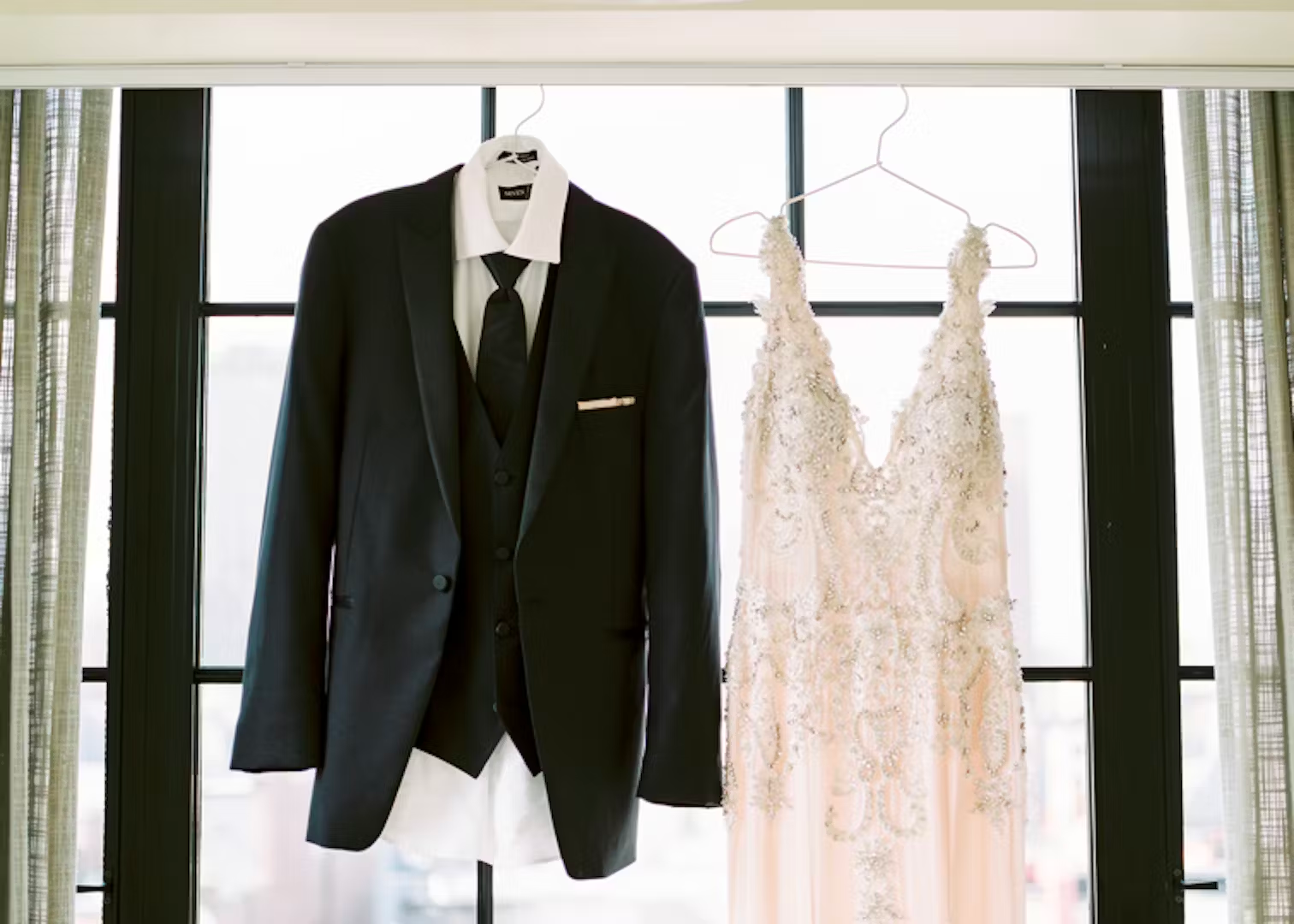 A suit and dress hanging in front of a window