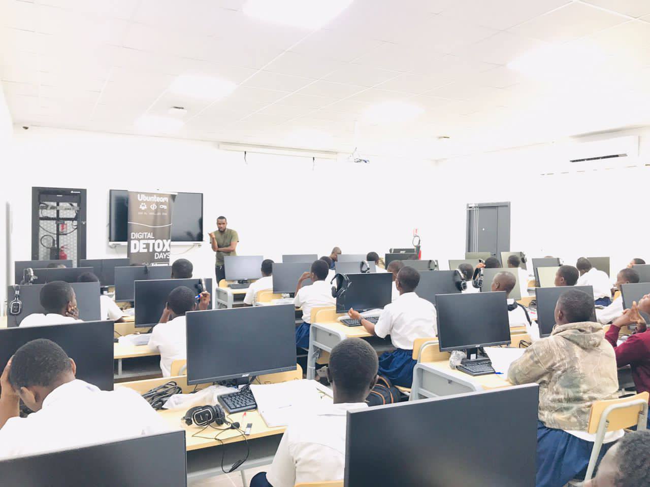 Full classroom with adolescent students seated in front of computer screens, listening to the trainer