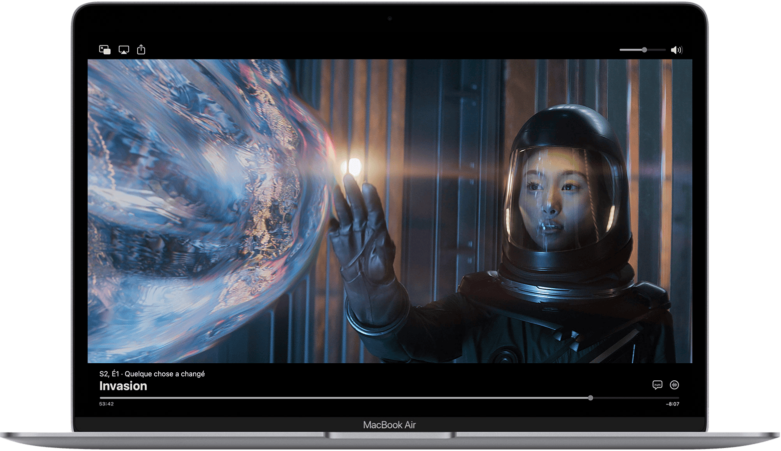 Sur un MacBook Air, l’app Apple TV est mise en pause et les commandes s’affichent. L’épisode est Something’s Changed from Invasion. En bas à droite, le bouton Langue des sous-titres et le bouton Audio se trouvent au-dessus de la barre de progression.
