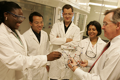 Researchers gathered around a molecular model.