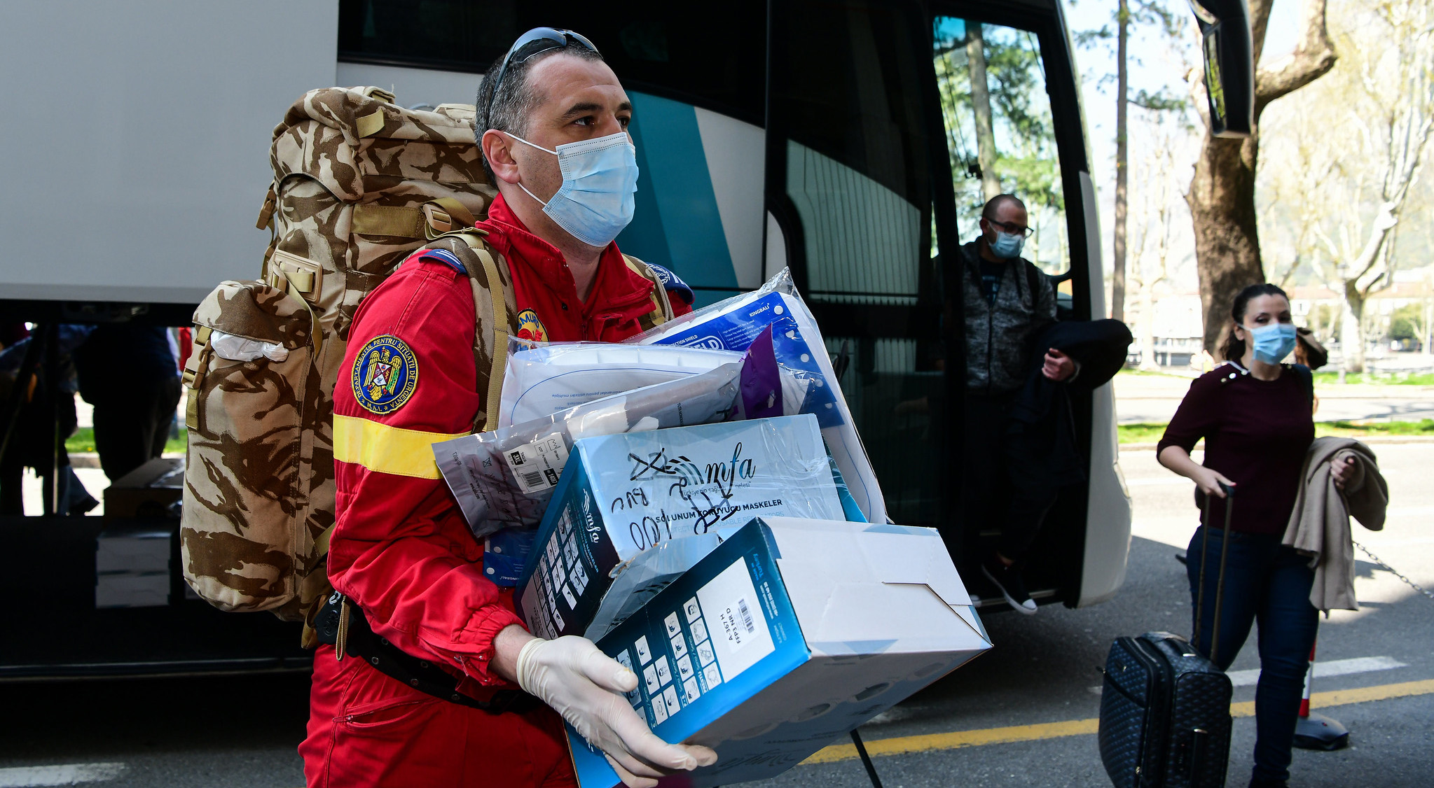 Aid worker carrying medical items in his arms