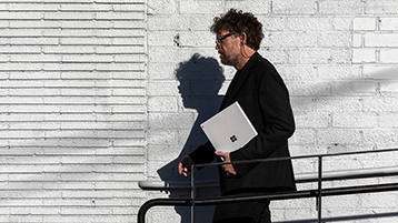 A man walking and holding Surface Book