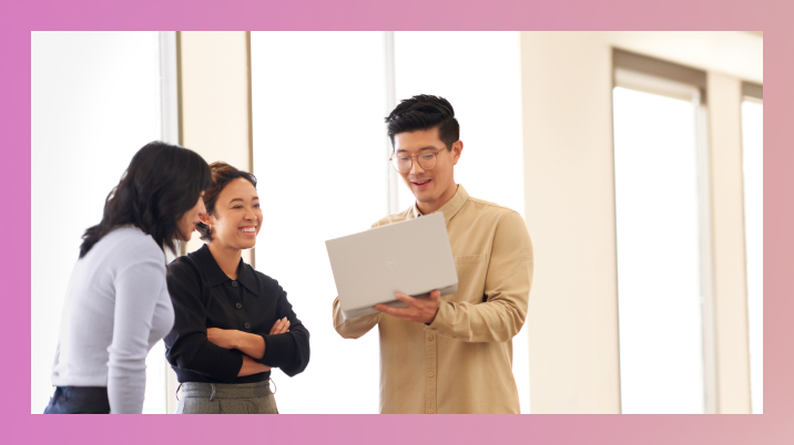 Three office workers standing looking at laptop