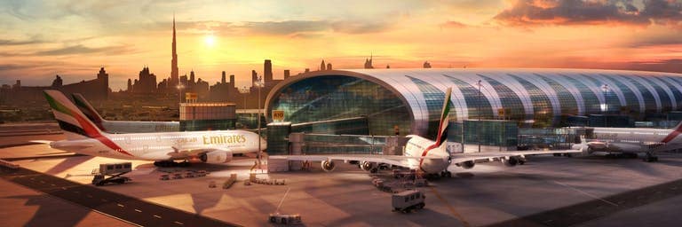 Des avions Airbus A380 d’Emirates à l’arrêt devant le Terminal 3 de Dubai International, avec le coucher de soleil sur Dubai en toile de fond