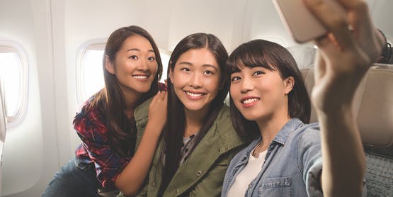 three passengers taking a selfie together in Emirates Economy Class