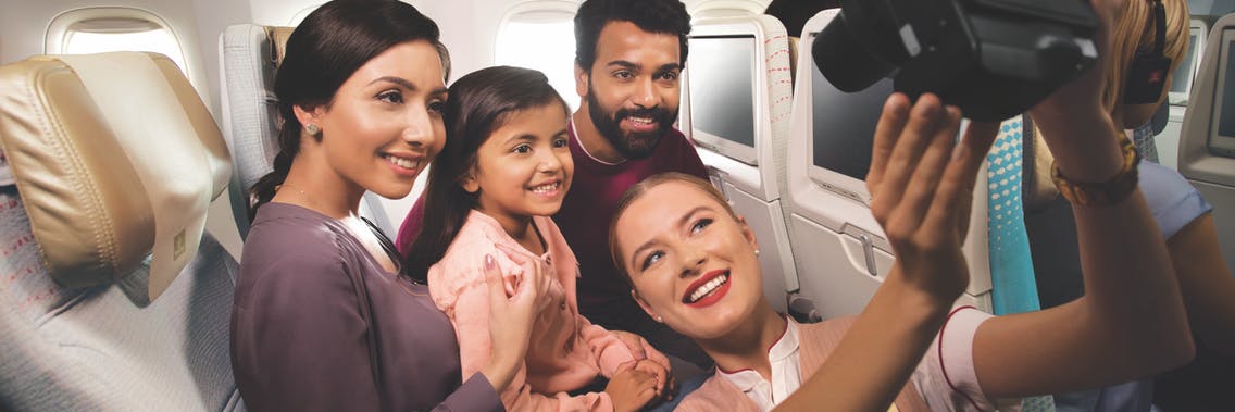 cabin crew taking a selfie with a family in Emirates Economy Class