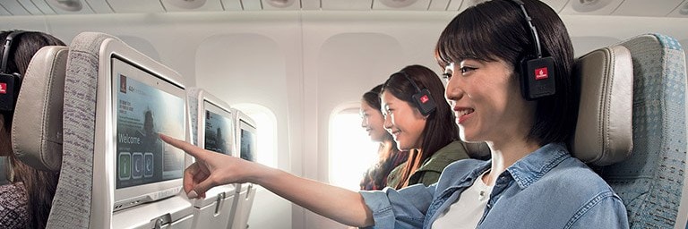 three passengers choosing inflight entertainment in Emirates Economy Class