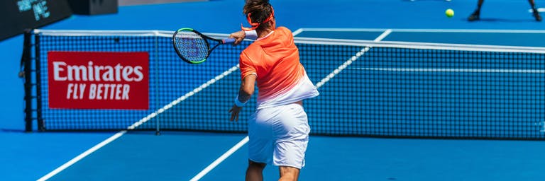 man hitting a ball with his tennis bracket on a tennis court