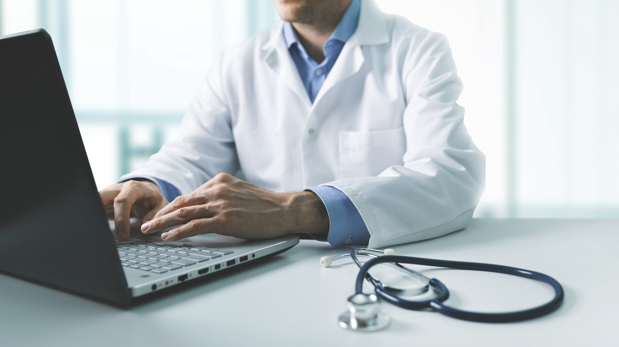 online medical consultation - doctor working on laptop computer in clinic office. copy space