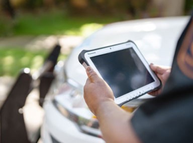 Police officer holding and looking at a rugged device