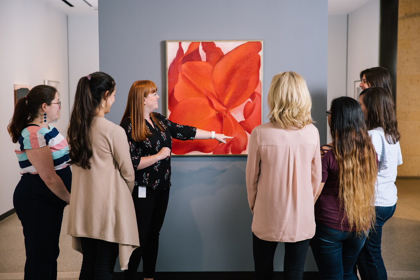 Group of people on a tour at the Carter stand in front of a painting of a flower.