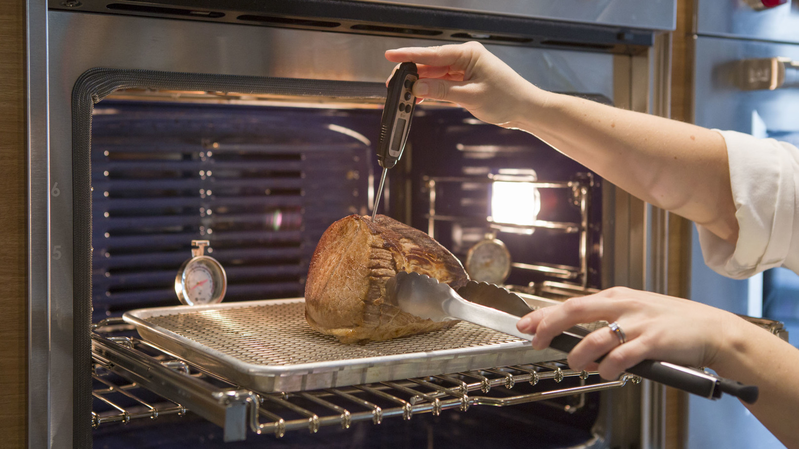 Thermometer taking temperature of roast in the oven