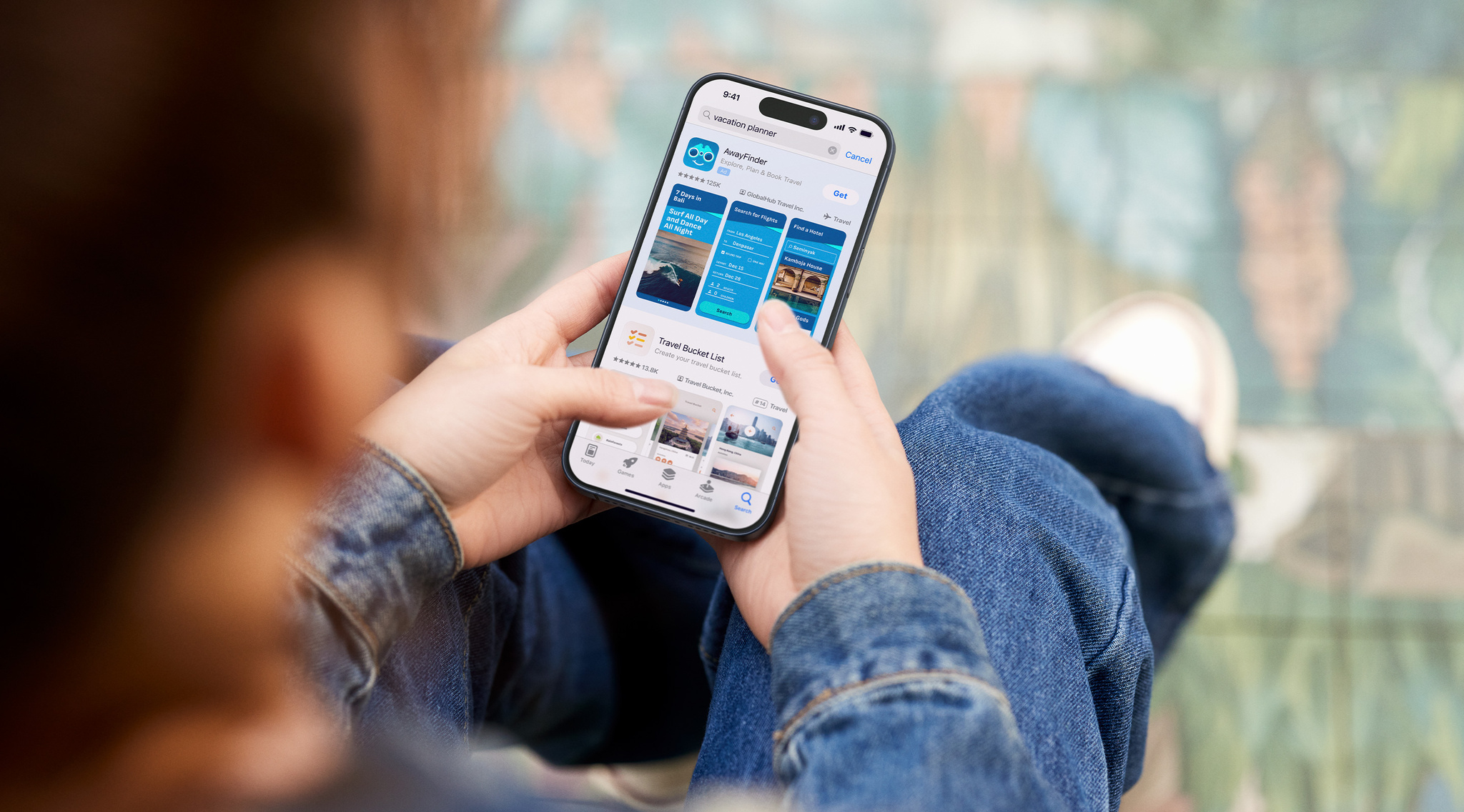 A person holds an iPhone that shows examples of Apple Search Ads, which appear at the top of the screen for an app called AwayFinder.