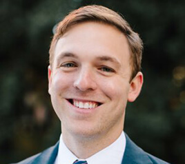 A person in a suit and tie smiles.