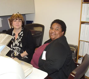 Two women sitting at a desk in an office.