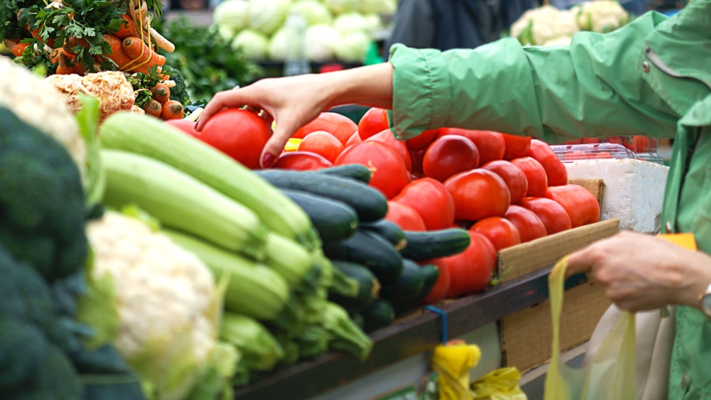 A person picks up a fruit at a market.