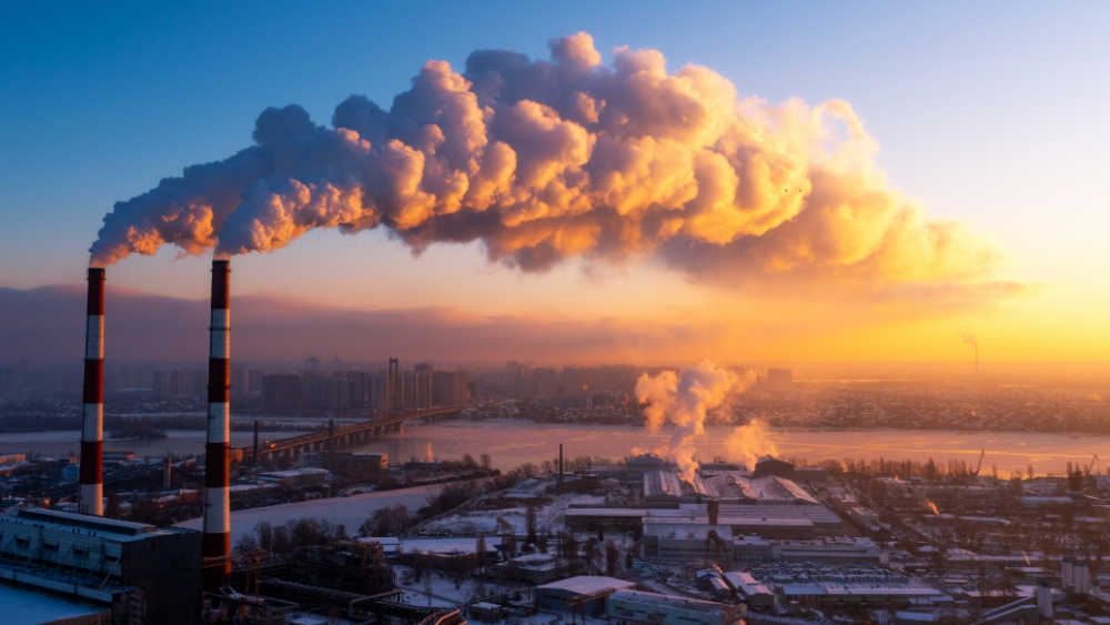 Two chimneys standing in an industrial area and smoke is coming out