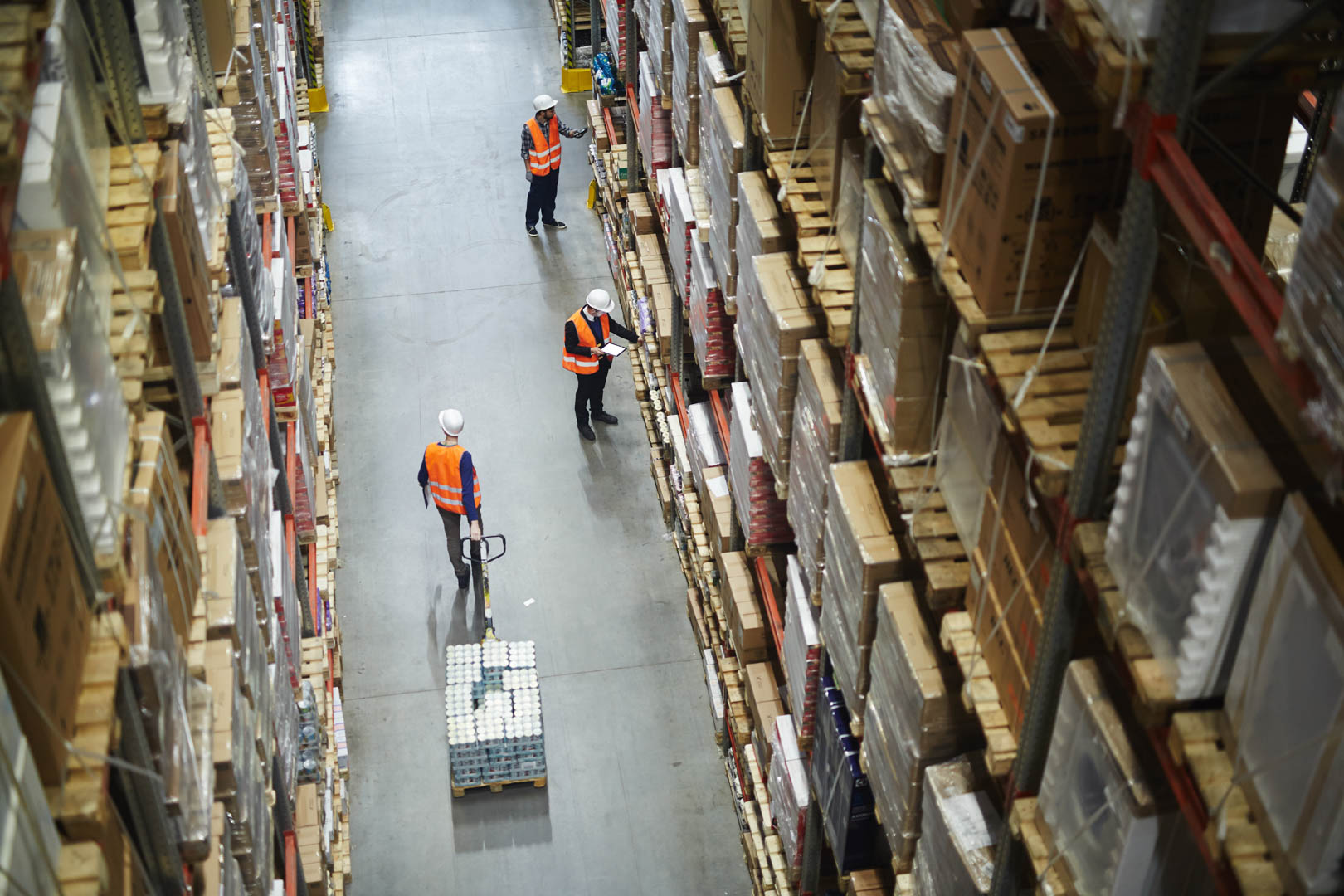 aerial view of warehouse workers with safety vests and hard hats walking through factory