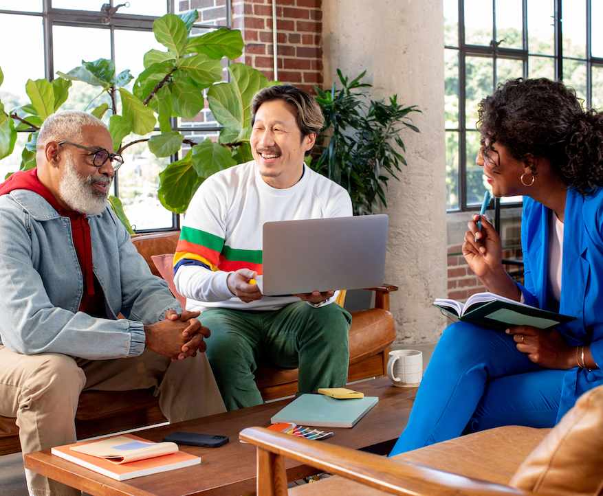 Three people having a meeting on comfortable couches in a sunlit room