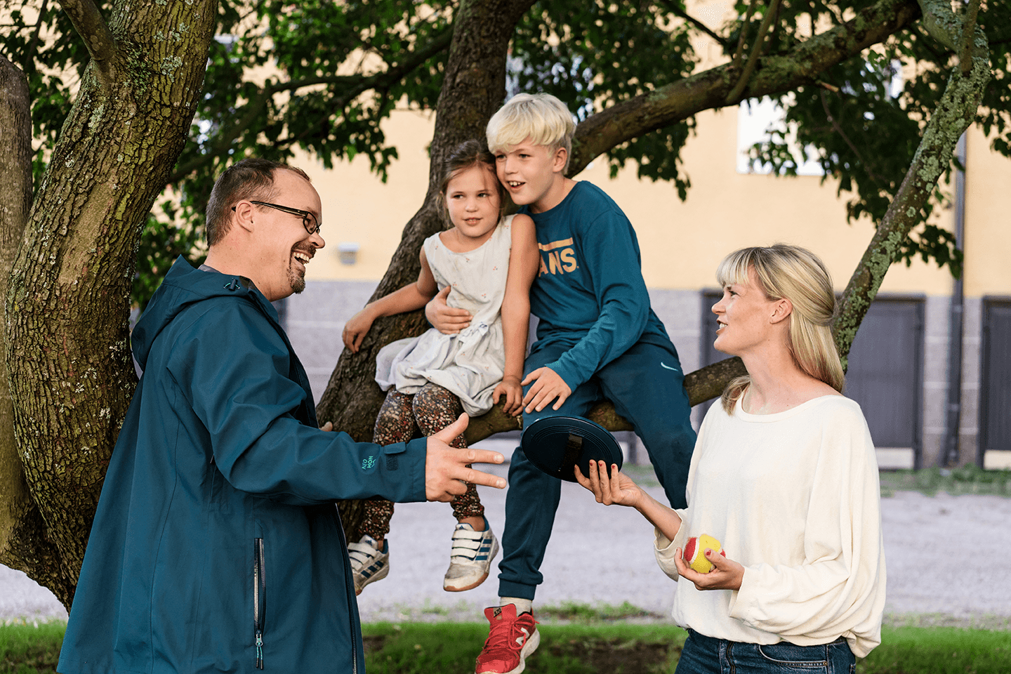 Två barn sitter i ett träd. Föräldrarna diskuterar.