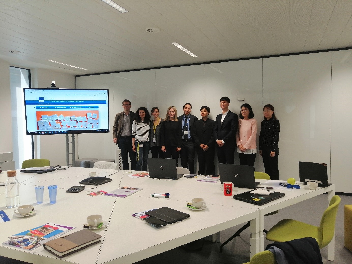 Image: Group of people posing for a picture in a meeting room around a table.