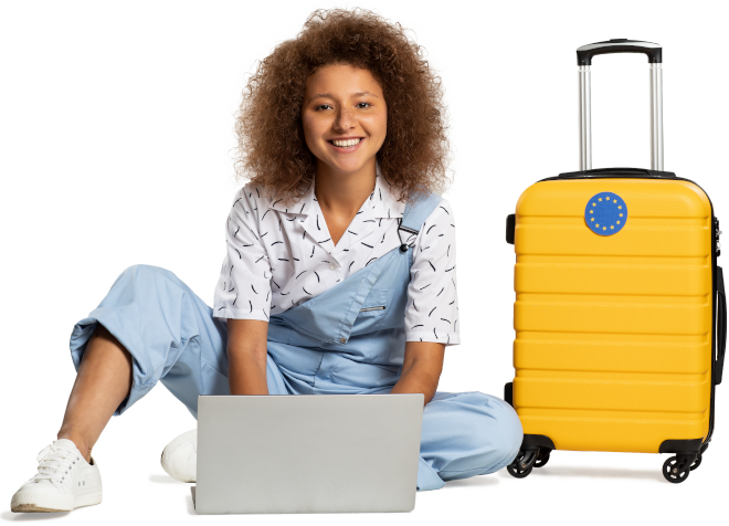 Enthusiastic young woman sitting on the floor next to a suitcase and typing on a laptop